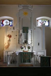Pulpit altar in the church of Tauche during restoration, shown in liturgical use while wall paintings remain partially uncovered