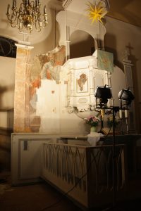 Pulpit altar in the church of Tauche illuminated with work lights during restoration, documenting active conservation of the altar wall painting