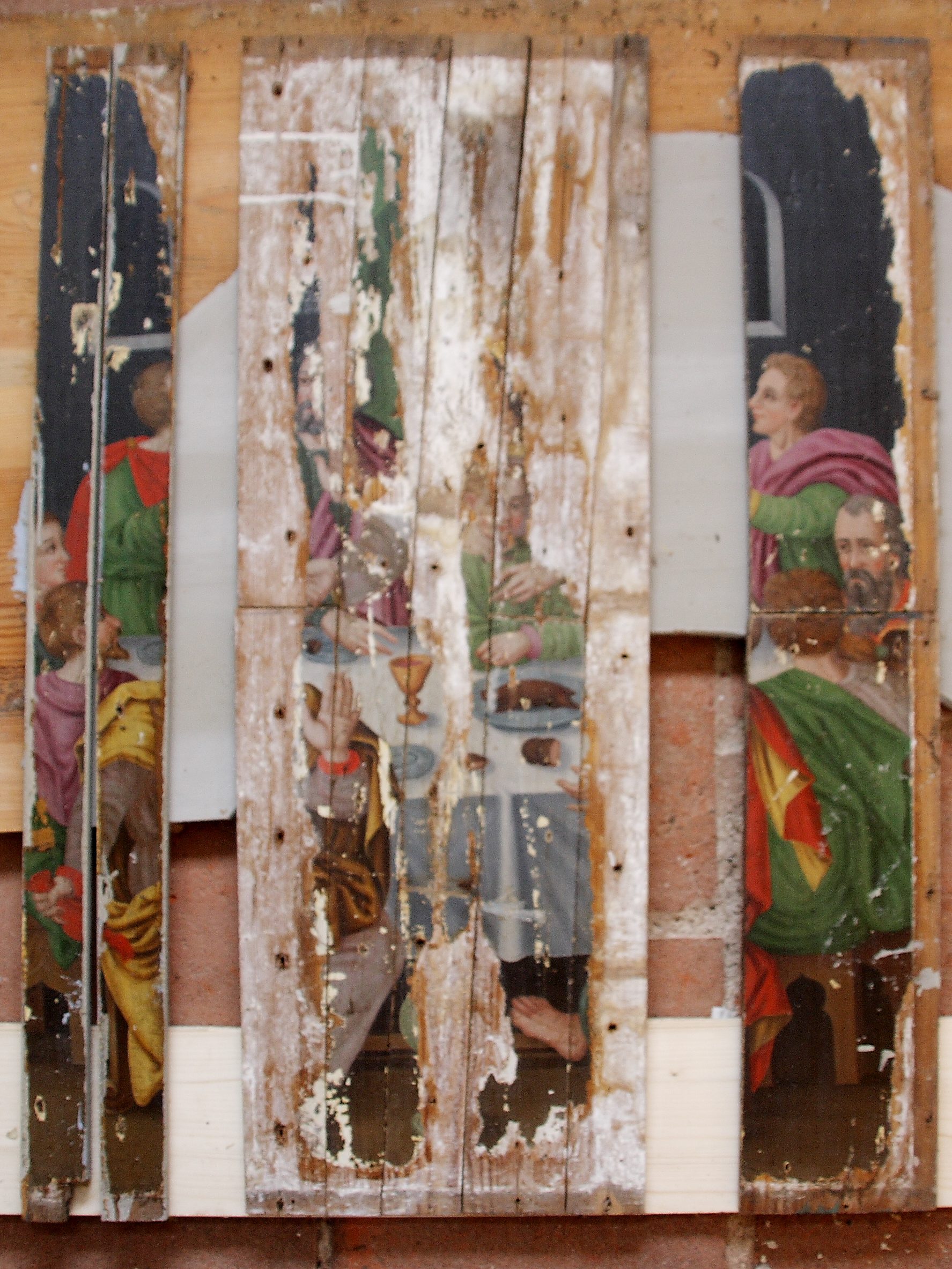 Dismantled wooden panels with fragments of the Last Supper painting, showing paint loss and surface damage during restoration of the pulpit altar