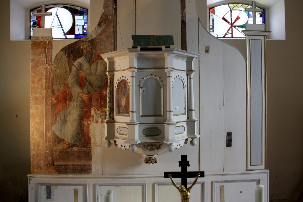 Early restoration stage of the south altar wall, where only the eye of the painted figure is visible beneath later surface layers